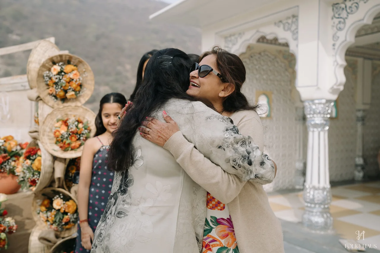 Two guests embracing in a sunlit courtyard at the Detox Mela.