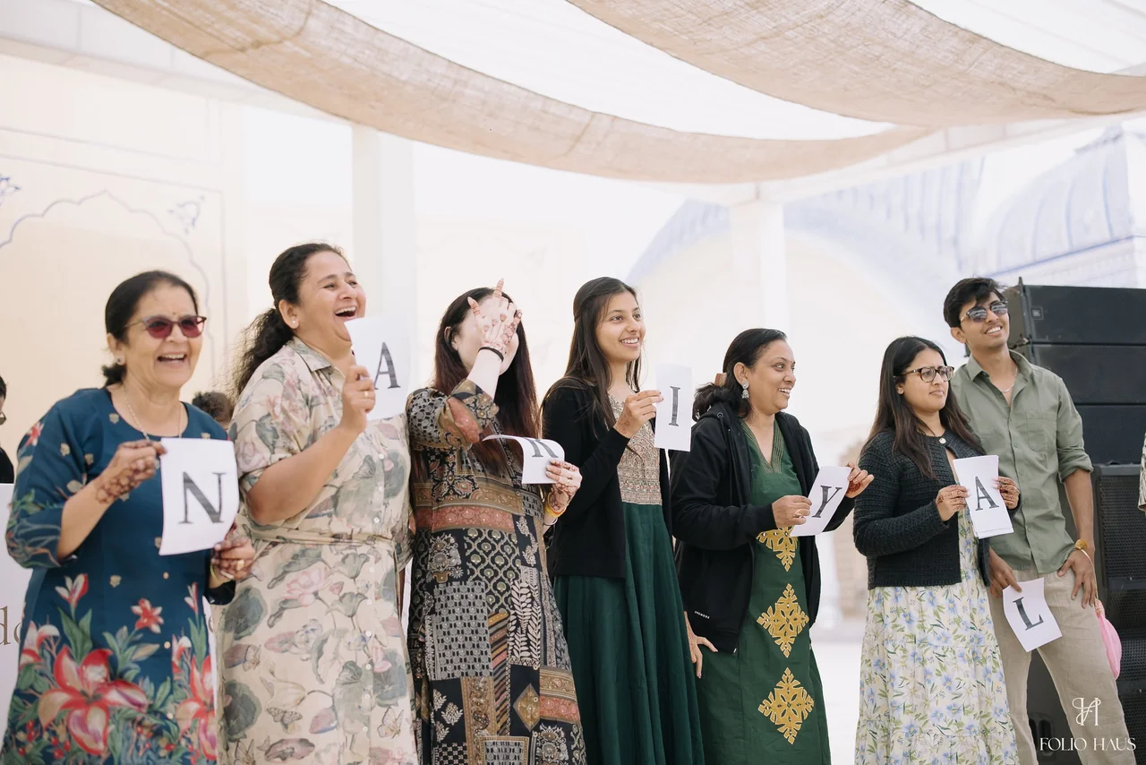 Guests taking part in a letter-card game beneath fabric canopies.