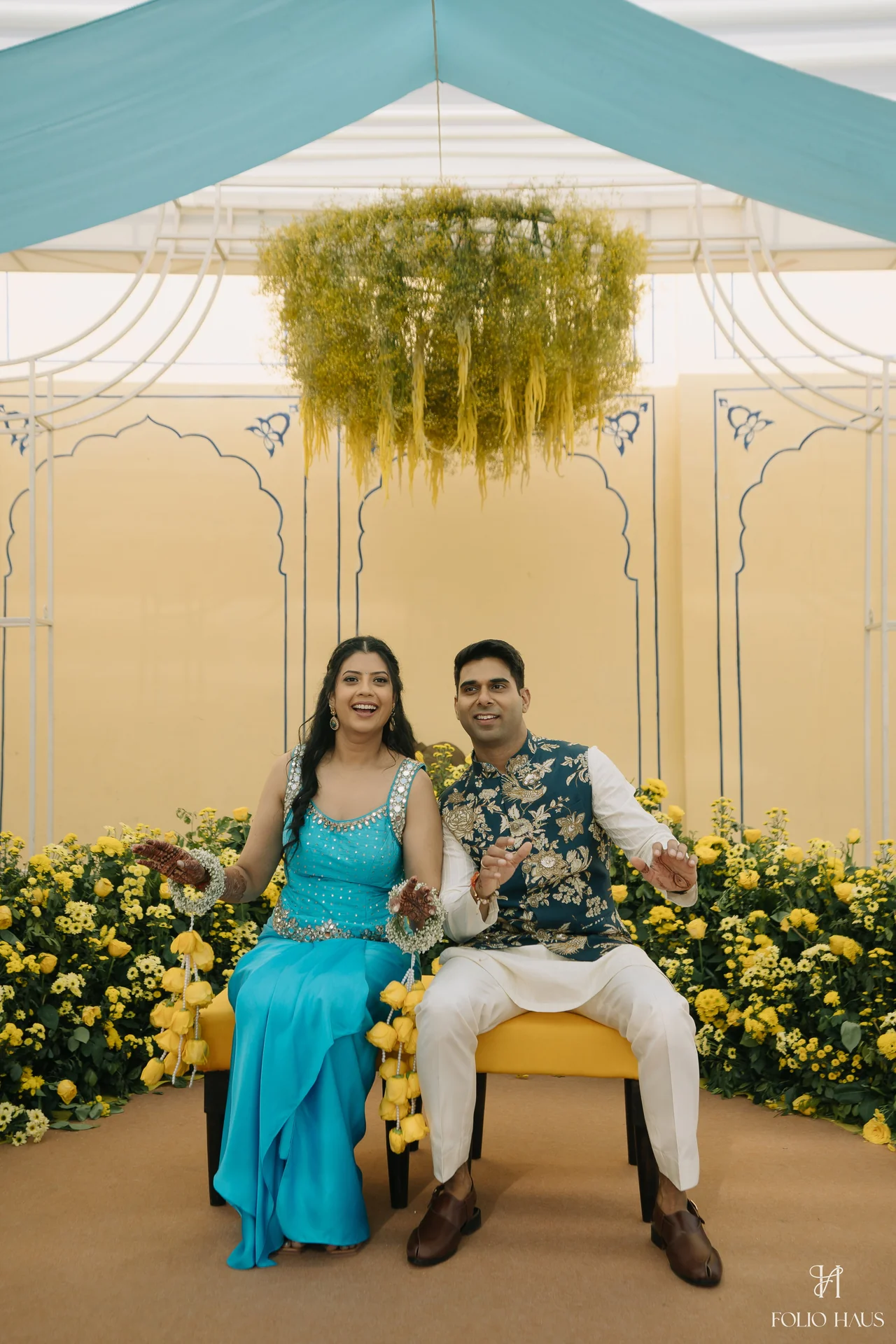 Jigna and Anurag seated together beneath blue and white draped fabric.