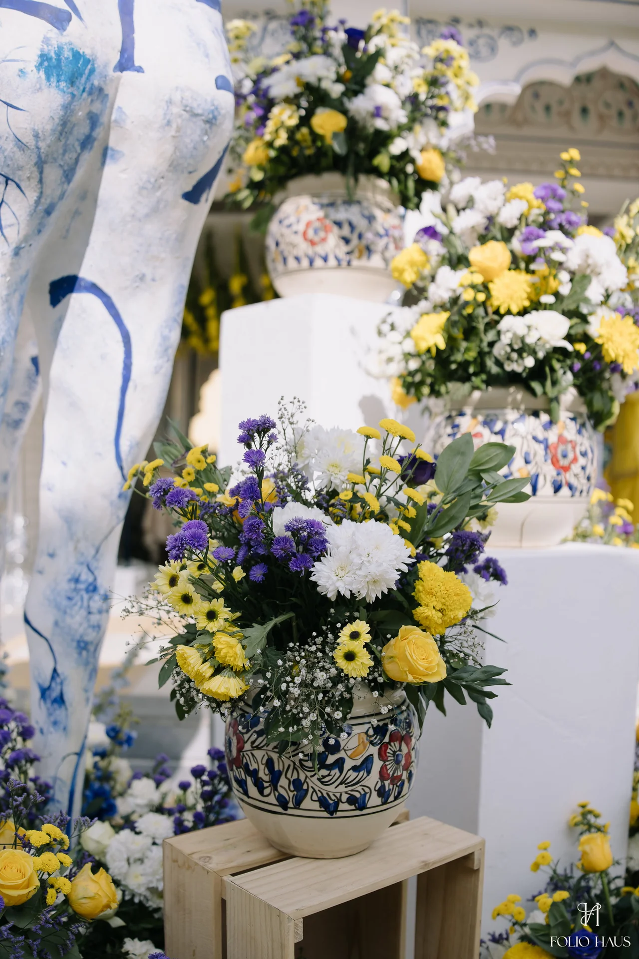 Yellow and blue flowers arranged beside a painted decorative figure.