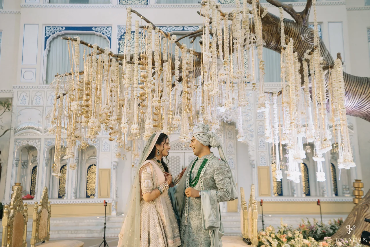 Jigna and Anurag together beneath hanging wedding flowers.