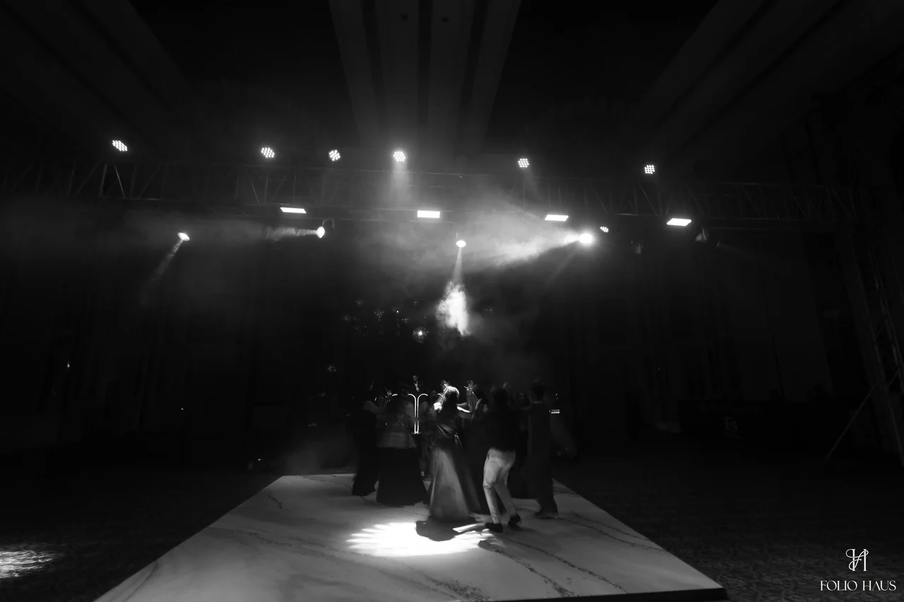 A black and white photograph of a dancer beneath after-party spotlights.