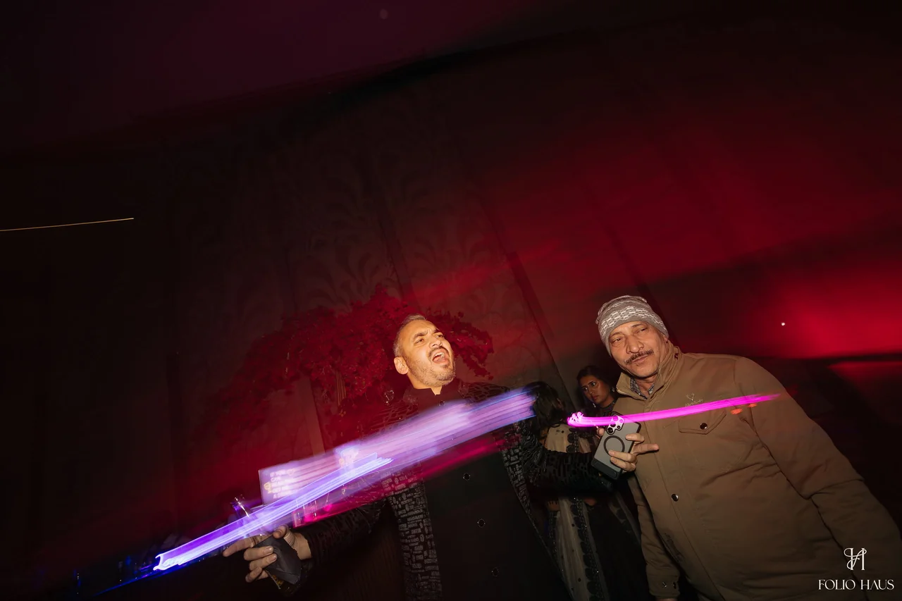 After-party guests dancing as bright colored light trails cross the frame.