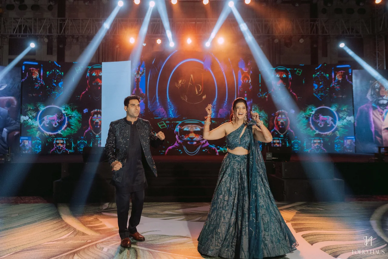 Jigna and Anurag dancing together on a stage beneath colored lights.