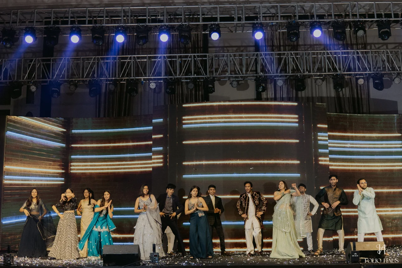 Wedding guests dancing together on the illuminated Sangeet stage.