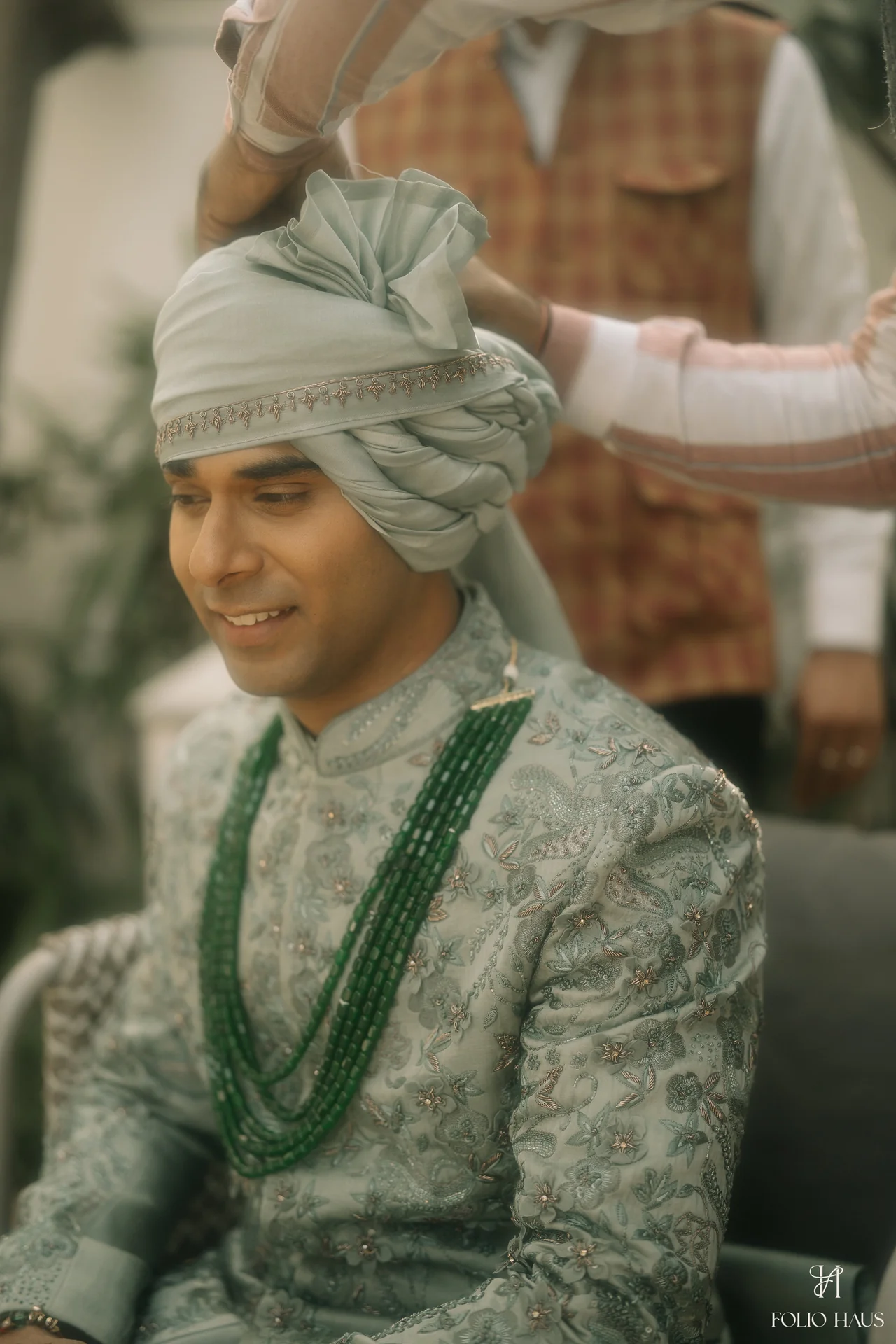 Anurag smiling while his wedding turban is being arranged.