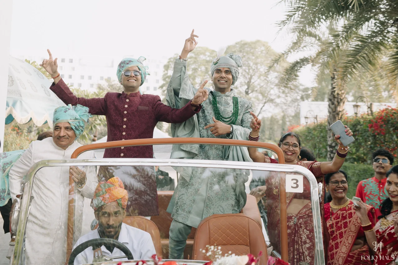 Wedding guests raising their hands from an open vehicle during the procession.