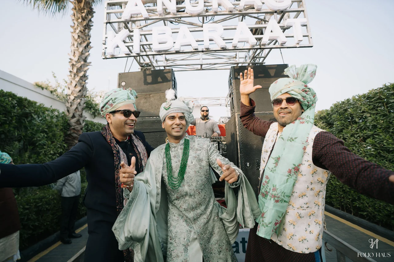 Anurag and guests dancing with raised hands during the wedding procession.