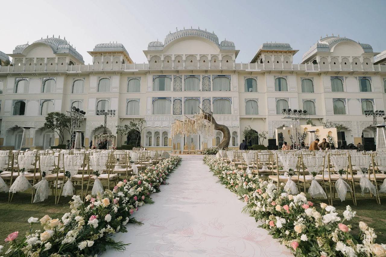 A flower-lined wedding aisle leading toward a pale palace facade.